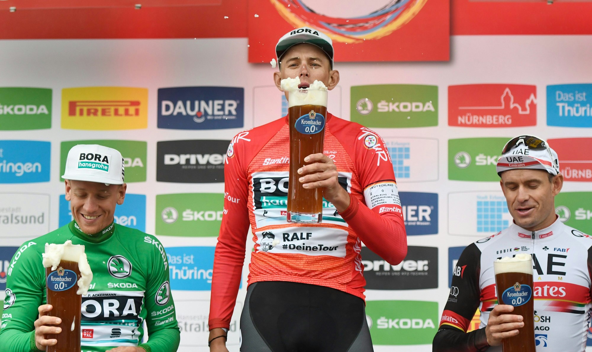 Pascal Ackermann (l-r) aus Deutschland vom Team Bora-Hansgrohe im Grünen Trikot des Sprintbesten, Nils Politt aus Deutschland vom Team Bora-Hansgrohe im Roten Trikot des Gesamtführenden und der Norweger Alexander Kristoff vom UAE Team Emirates stehen nach der Etappe auf dem Podium.