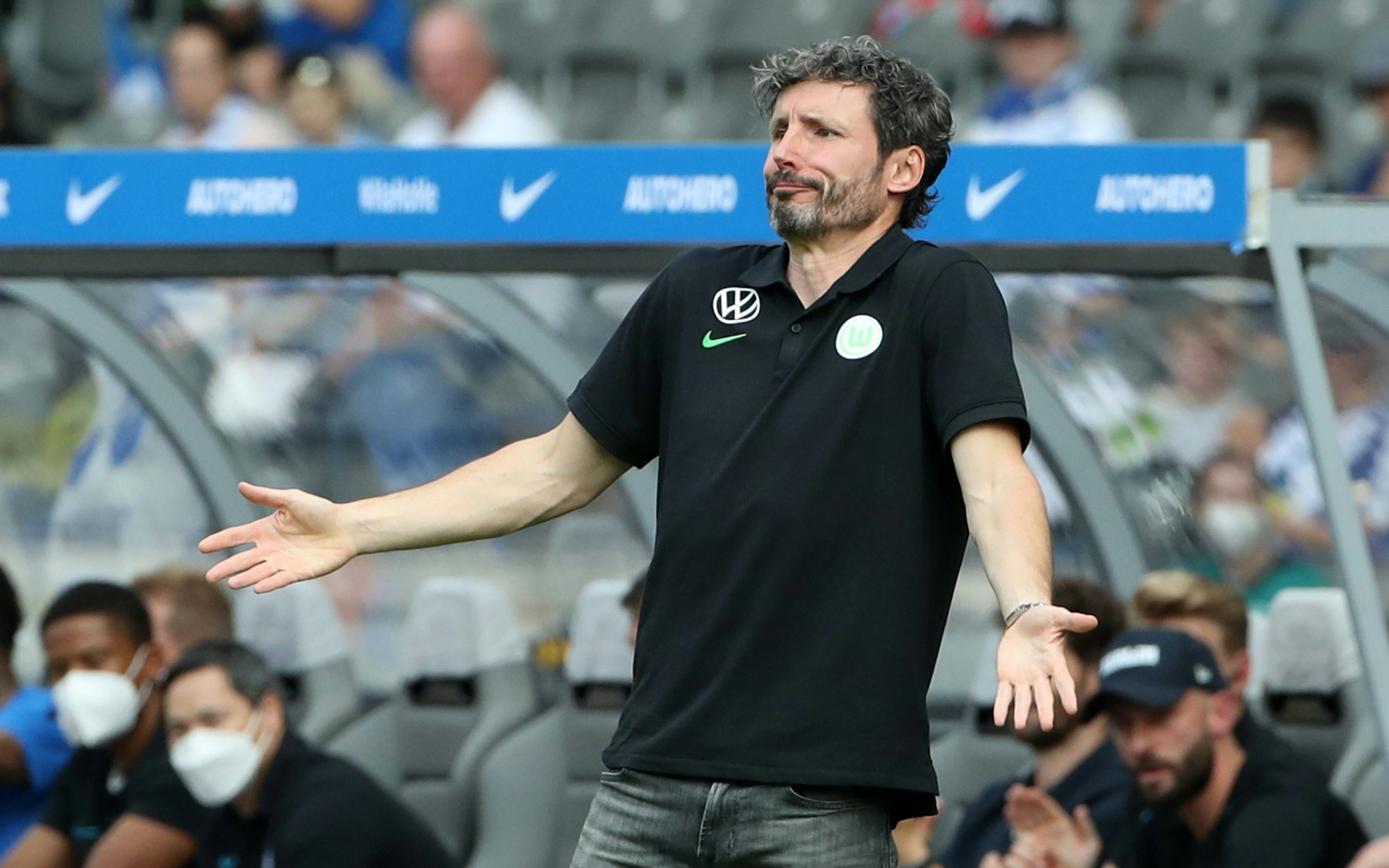 Mark van Bommel steht vor der Trainerbank und breitet fragend die Arme aus.