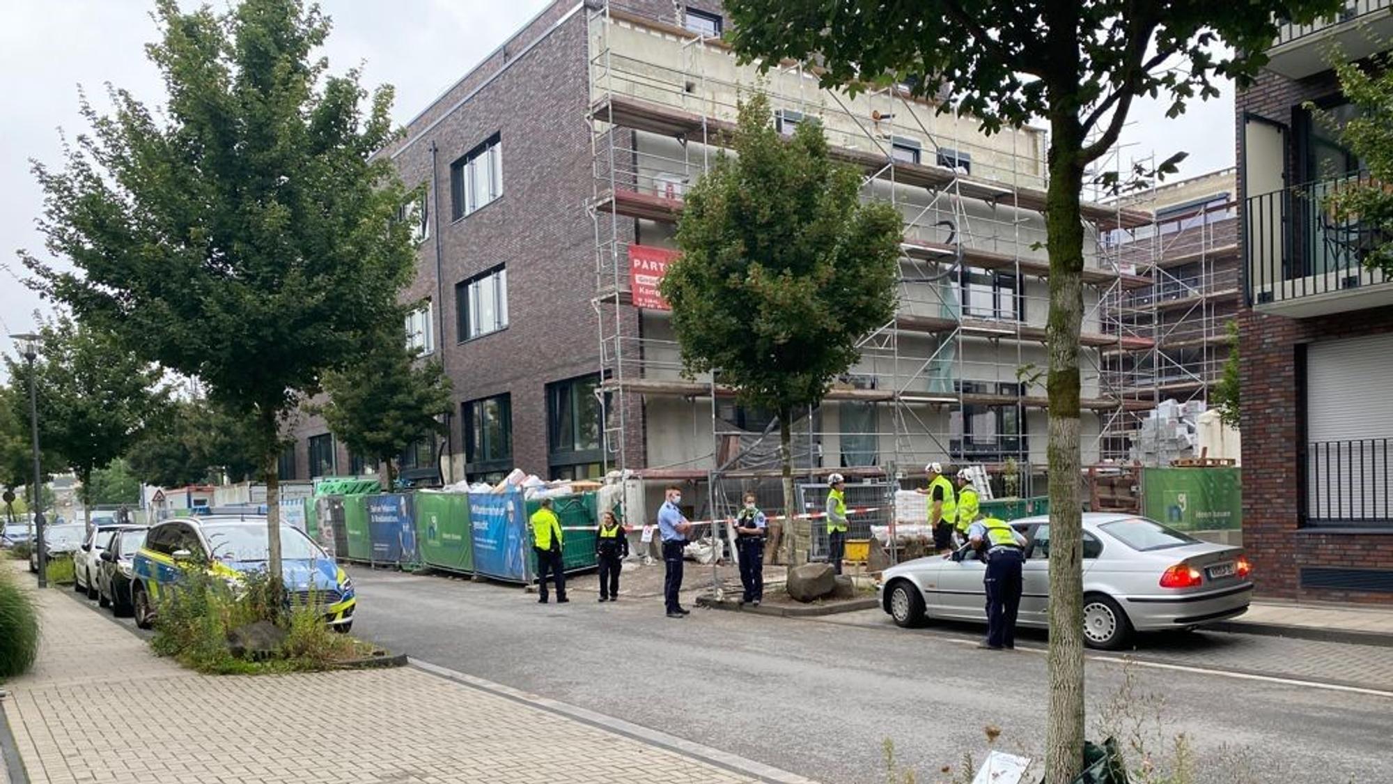Mehrere Personen stehen vor einer abgesperrten Baustelle.
