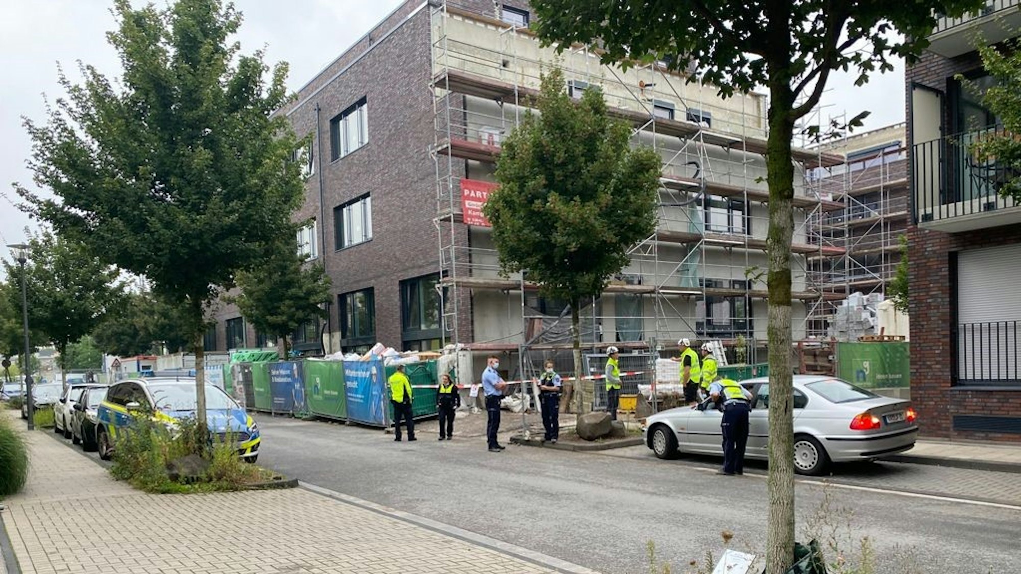 Mehrere Personen stehen vor einer abgesperrten Baustelle.