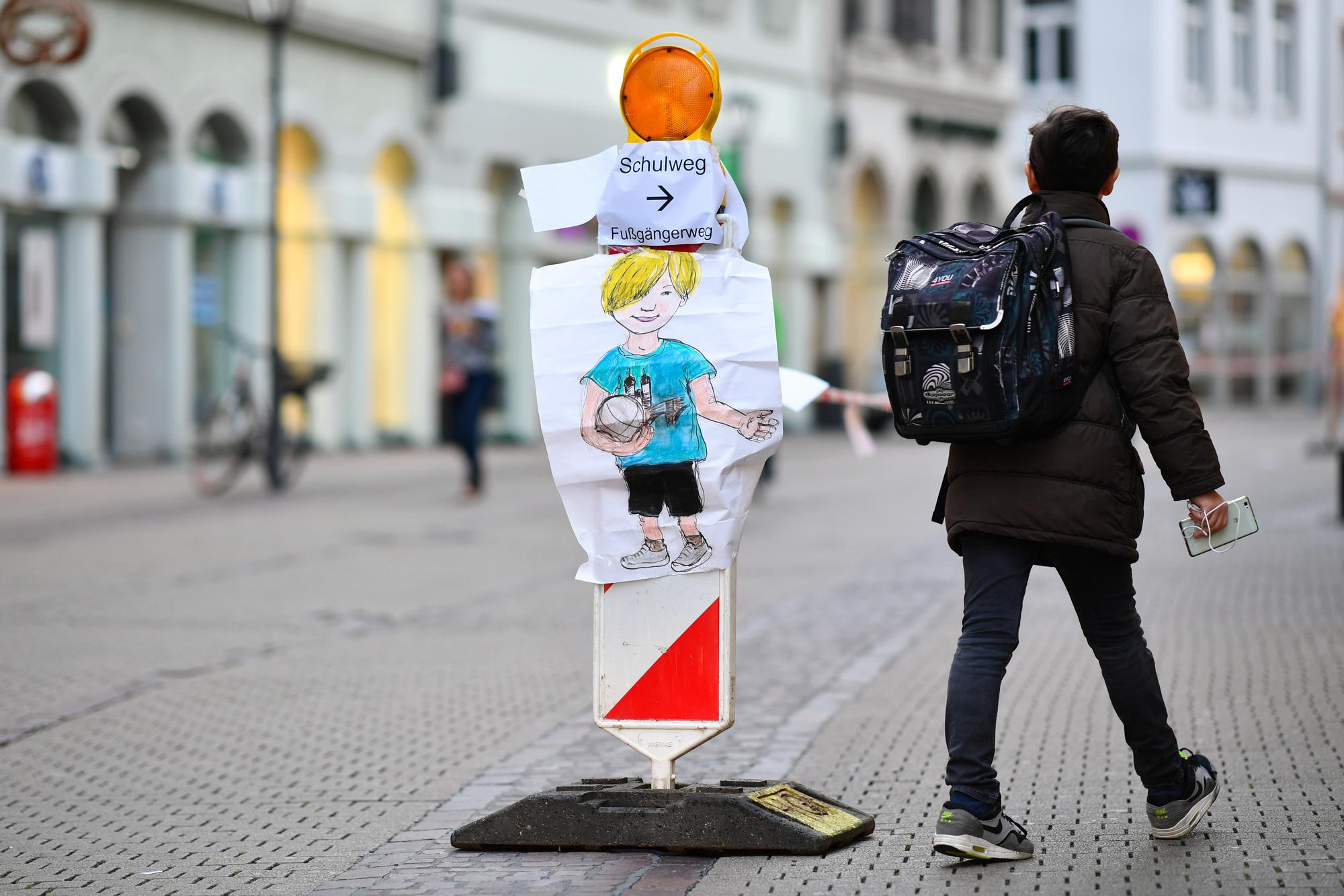 Ein Junge geht am 04.10.2017 in Heidelberg (Baden-Württemberg) in der Hauptstraße an einer Straßenabsperrung mit Absperrband vorbei, an der ein Zettel mit der Aufschrift „Schulweg “angebracht ist.