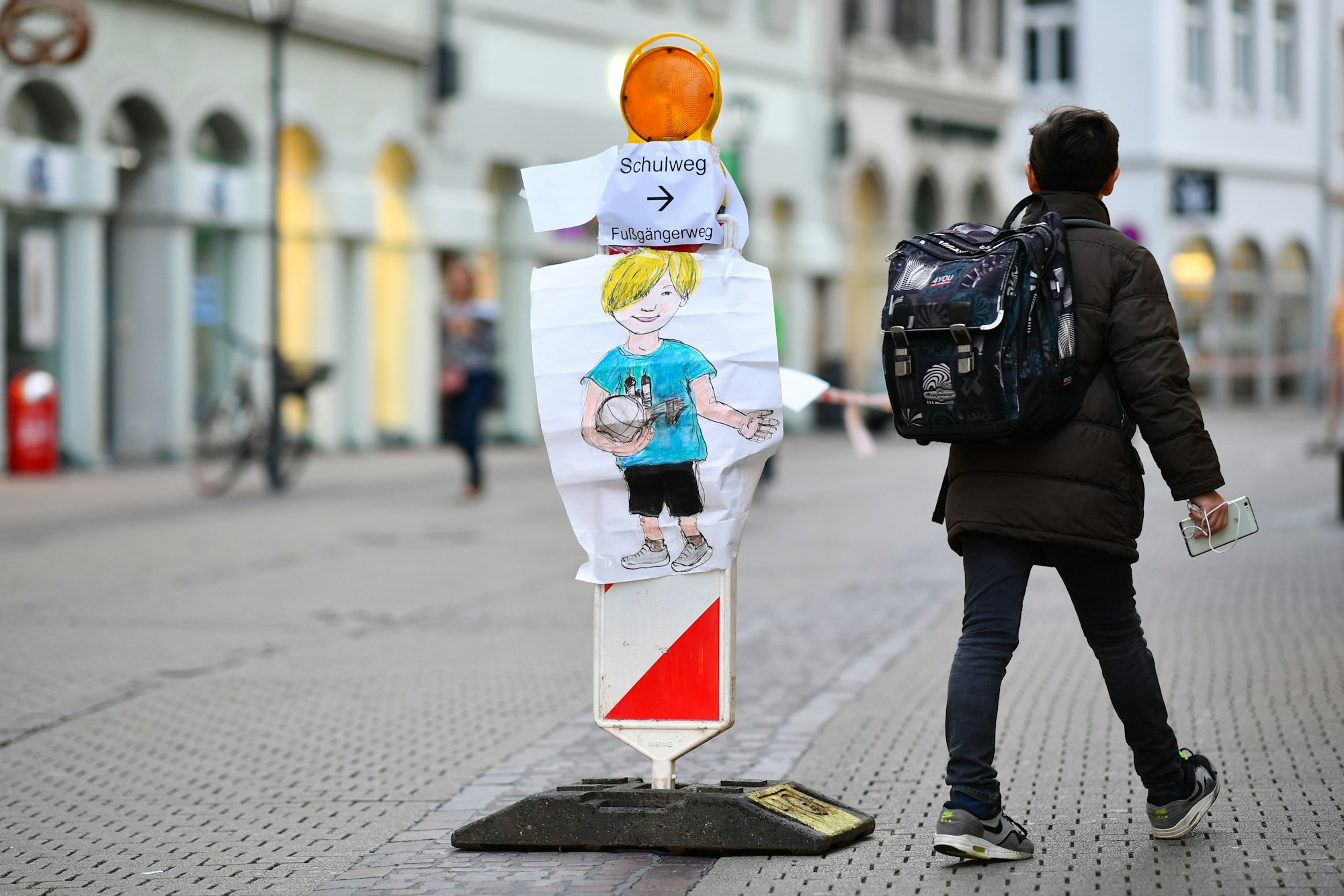 Ein Junge geht am 04.10.2017 in Heidelberg (Baden-Württemberg) in der Hauptstraße an einer Straßenabsperrung mit Absperrband vorbei, an der ein Zettel mit der Aufschrift „Schulweg “angebracht ist.