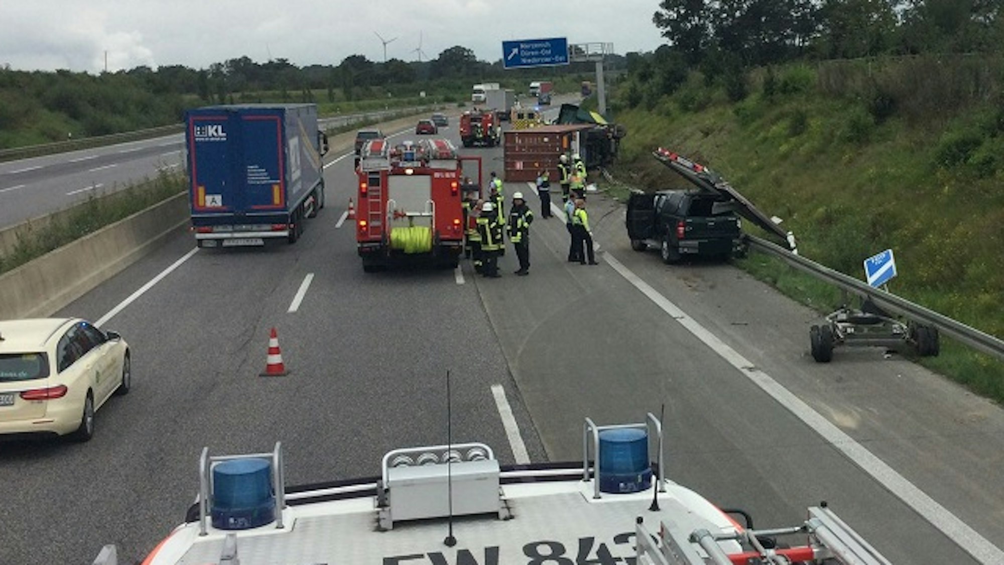Feuerwehrmänner und Polizisten stehen auf der Autobahn.
