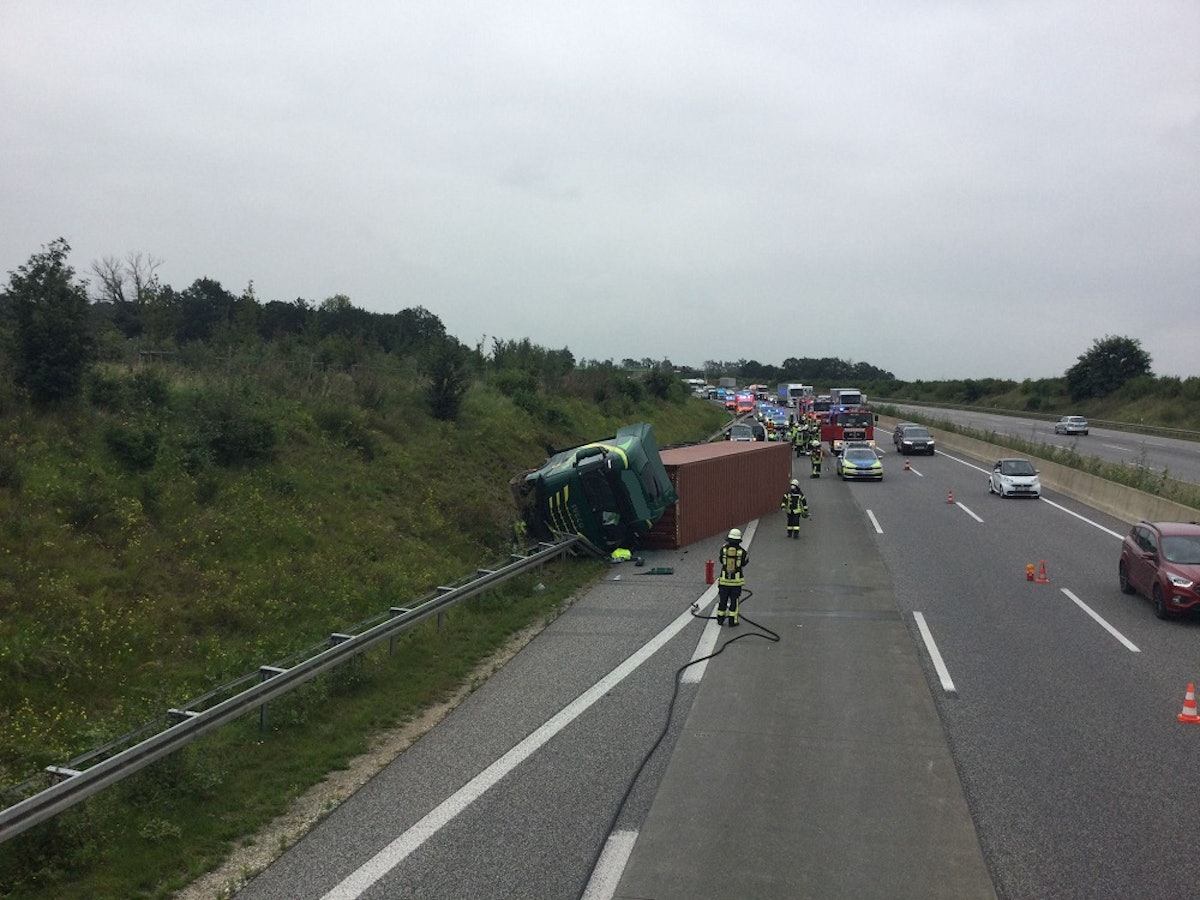 Ein Lkw liegt zur Seite gekippt auf der Leitplanke der Autobahn.