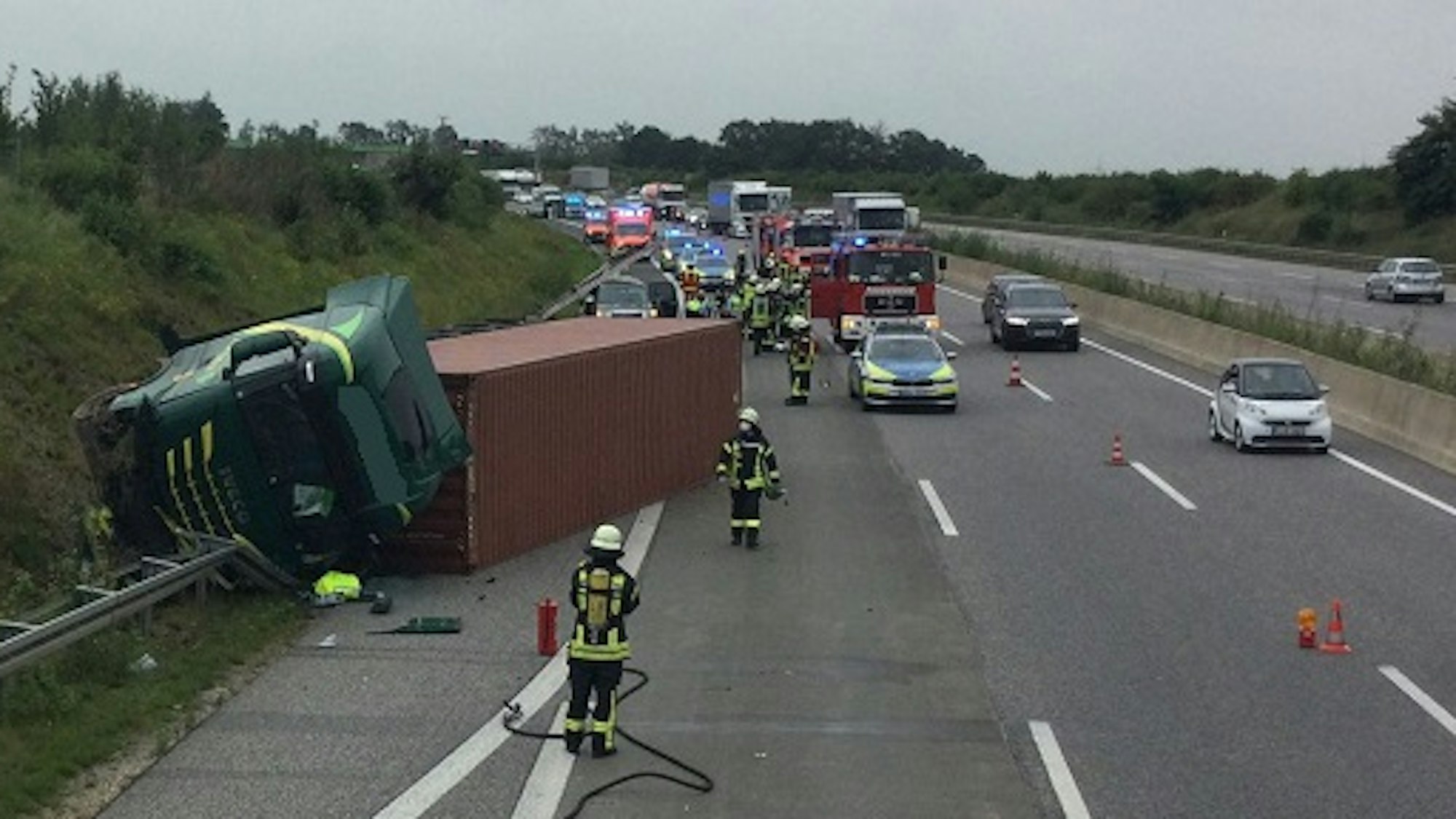Ein Lkw liegt zur Seite gekippt auf der Leitplanke der Autobahn.