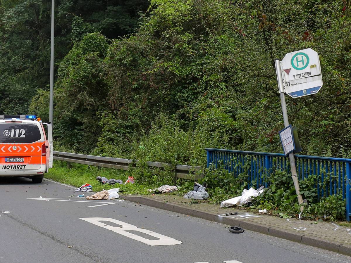 Das Schild einer Bushaltestelle ist umgebogen, ein kleines Rad und andere Gegenstände liegen davor verstreut.