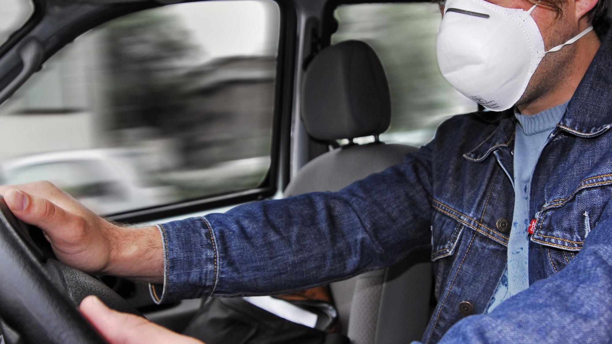 Ein Mann sitzt in unserem Symbolbild mit Corona-Mundschutz am Autosteuer: Ein betrunkener Fahrer ist in Ahlen in das Auto einer Frau gefahren und hat sie schwer verletzt. Nach einer dreisten Lüge flüchtete er.