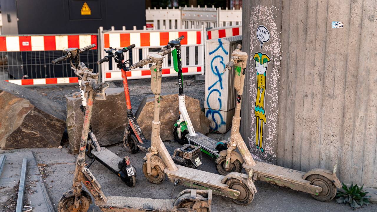 Verschlammte E-Scooter stehen an einer Mauer in Köln.