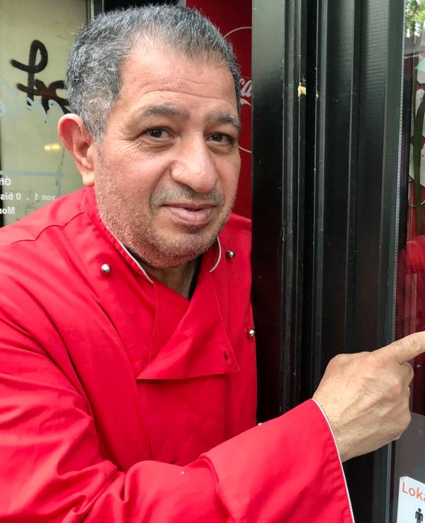 Carmelo Faraci zeigt auf den Jode-Lade-Aufkleber auf der Fensterscheibe des Lokals.