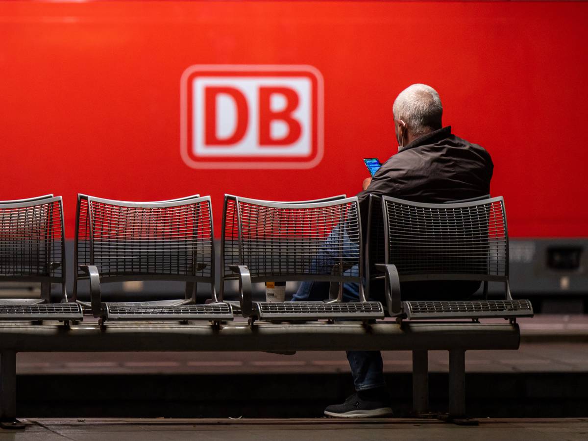 Das Logo der Deutschen Bahn (DB) prangt an der Seite einer Lok, während ein Mann in München am Donnerstag (2. September) auf dem Hauptbahnhof wartet. Die Deutsche Bahn geht gerichtlich gegen den GDL-Streik vor.