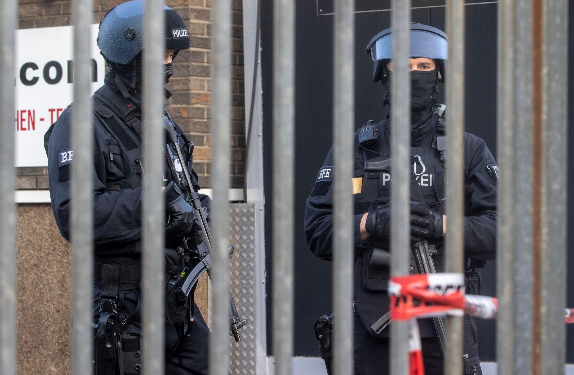 Polizisten stehen vor einem abgesperrten Gebäude.