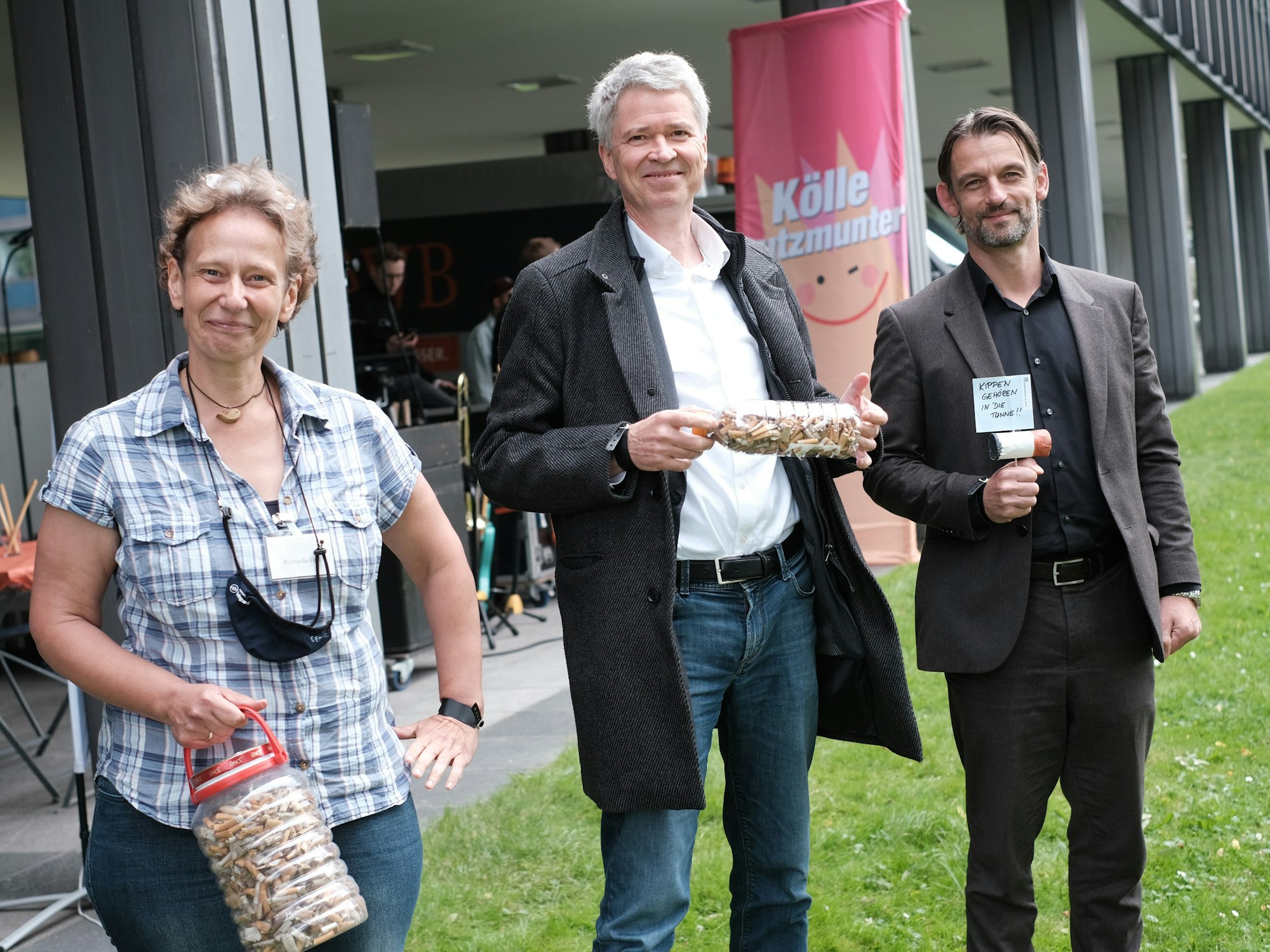 Richarda Fesl, Harald Rau und William Wolfgramm halten Dosen mit Zigarettenkippen in den Händen.