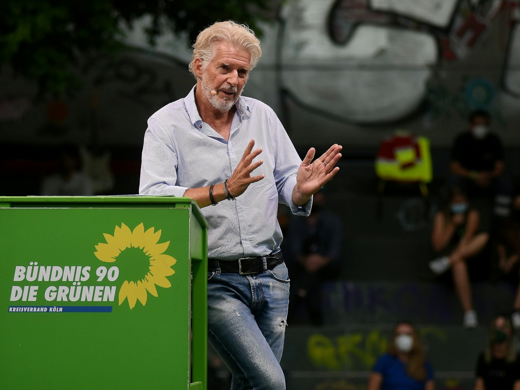 Frank Schätzing redet an einem grünen Pult auf dem Wilhelmsplatz.
