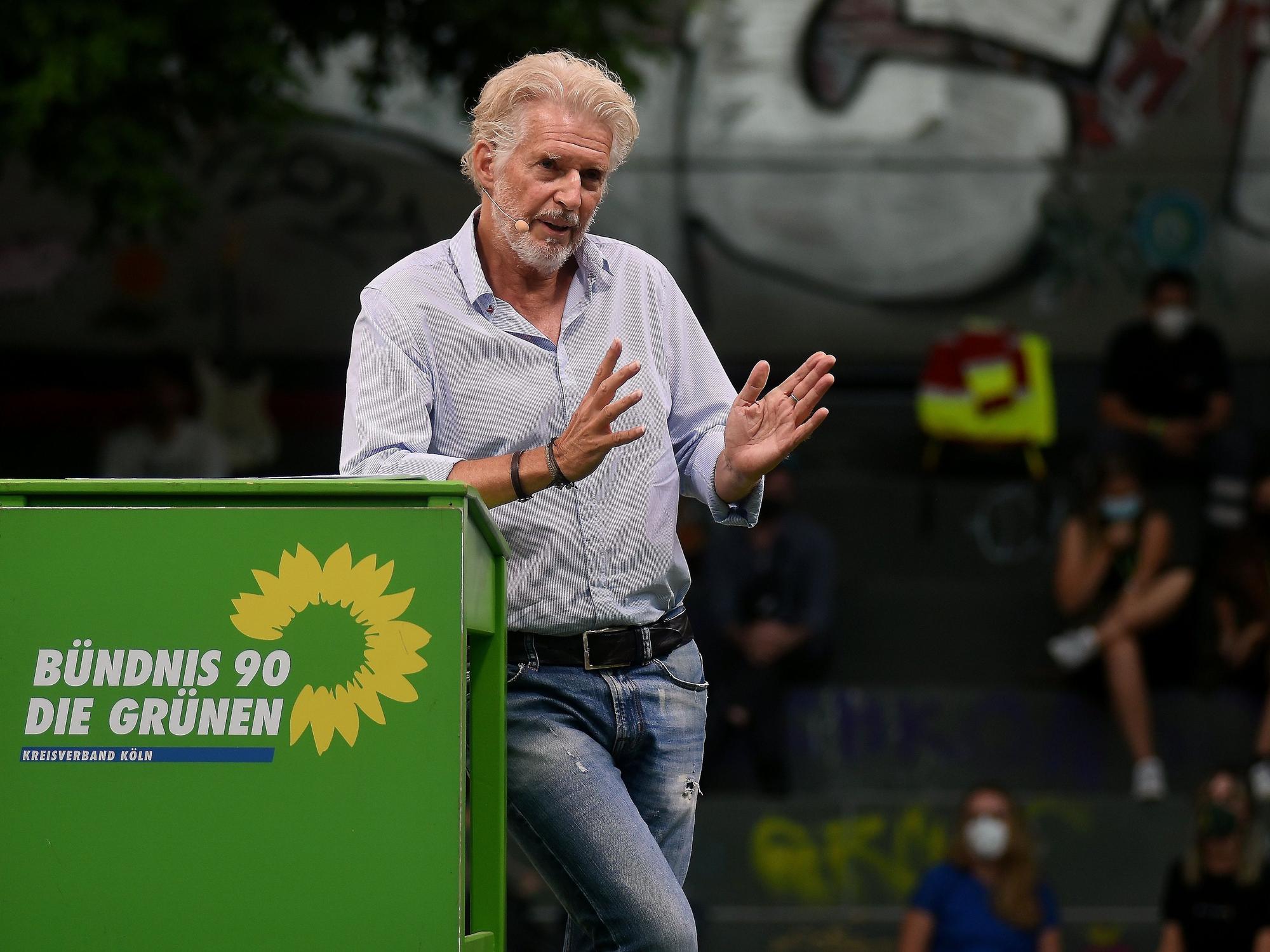 Frank Schätzing redet an einem grünen Pult auf dem Wilhelmsplatz.