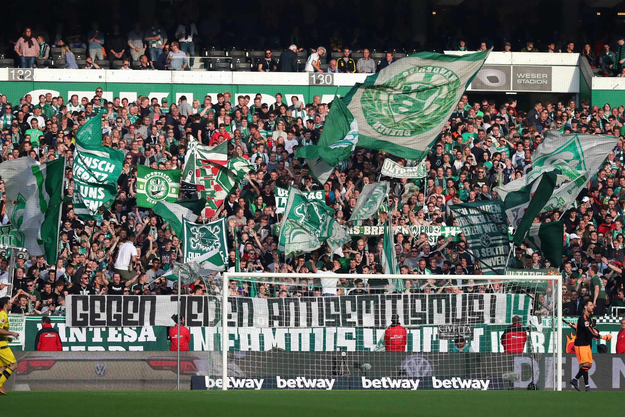 Vor der in Fahnen gehüllten Bremer Ostkurve hängt ein Transparent mit dem Schriftzug: „Gegen jeden Antisemitismus!“