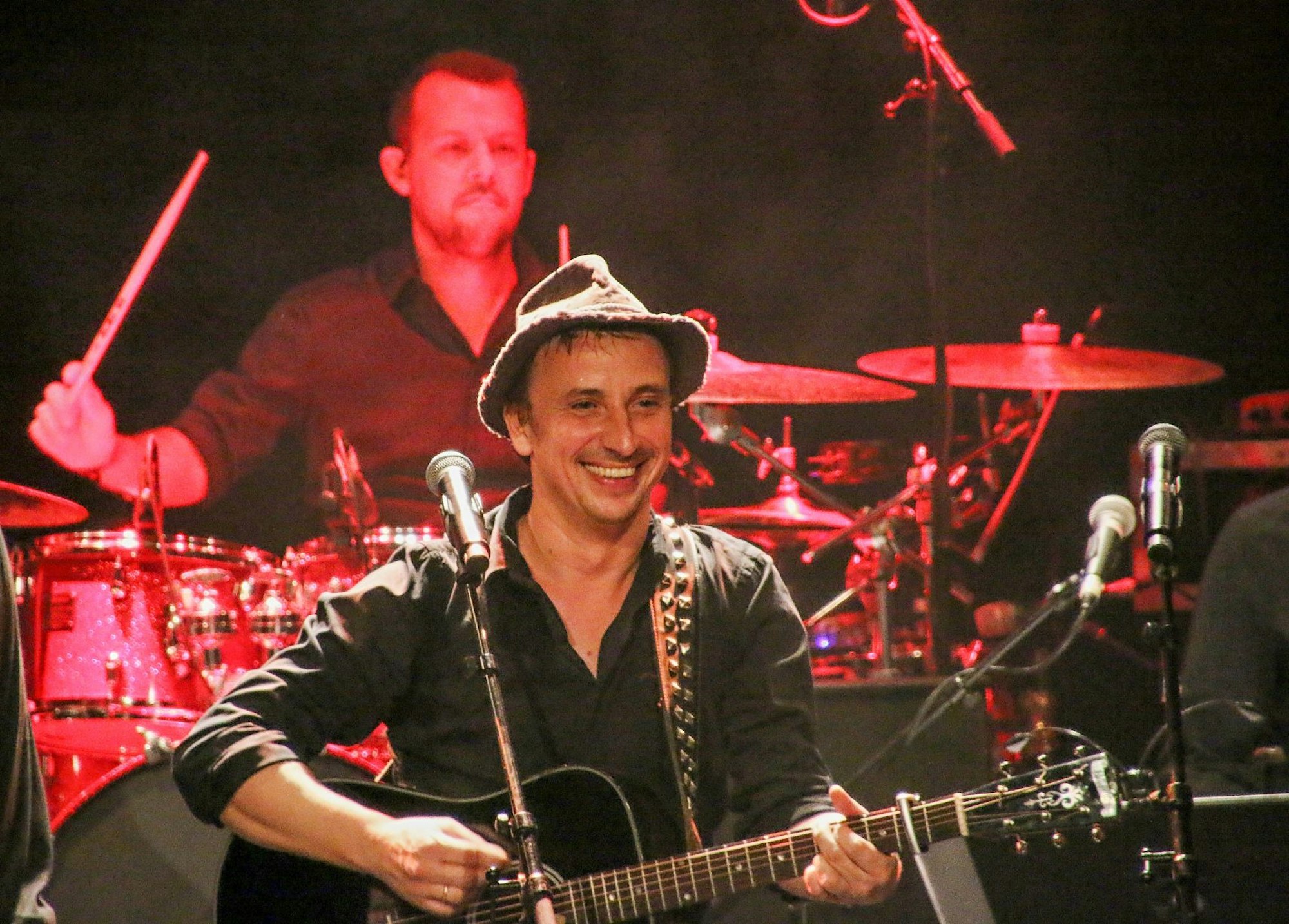 Stefan Knittler spielt auf der Bühne Gitarre und lacht.