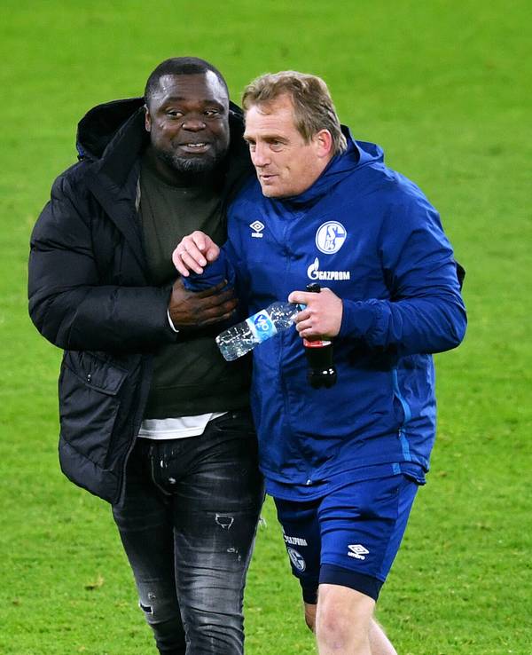 Asamoah und Büskens laufen Arm in Arm über das Feld.