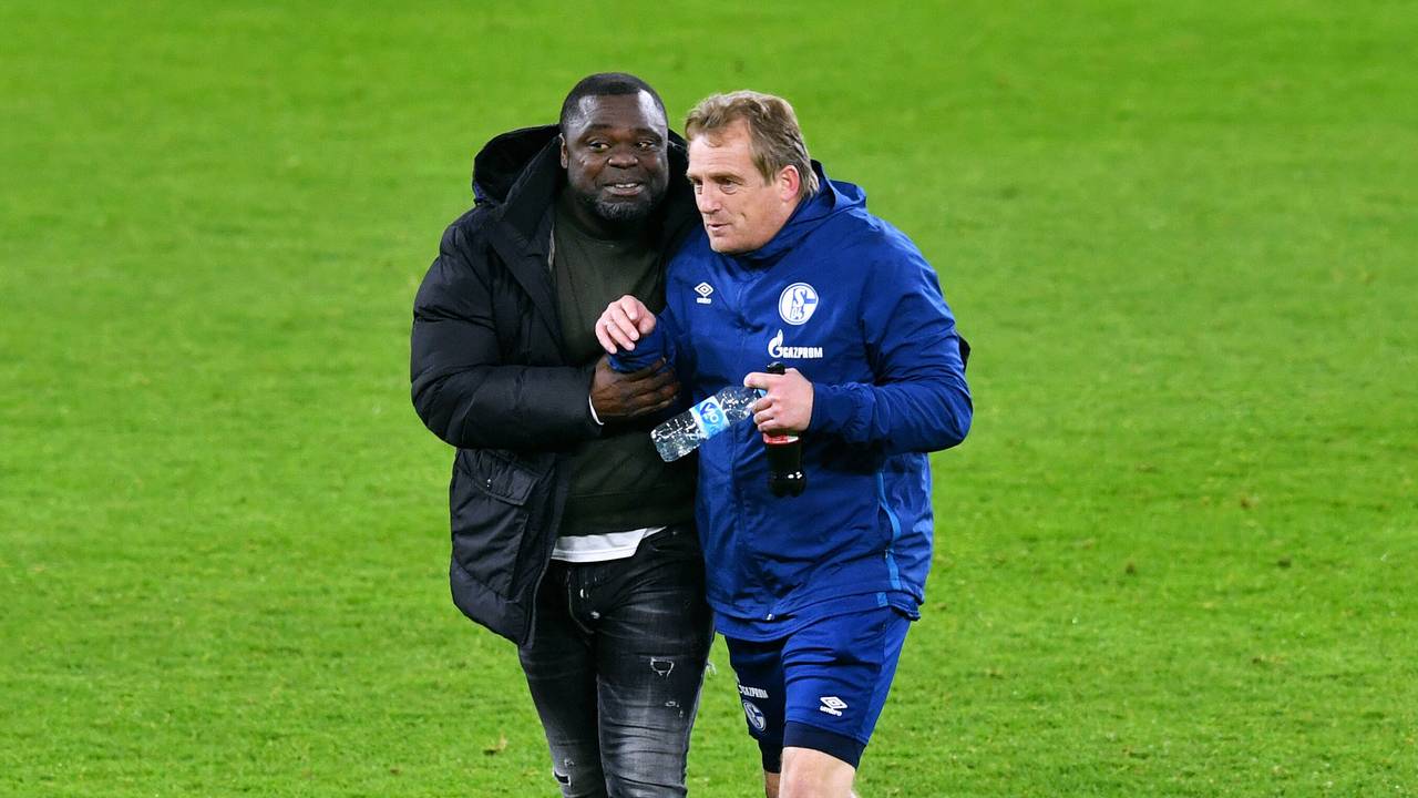 Asamoah und Büskens laufen Arm in Arm über das Feld.