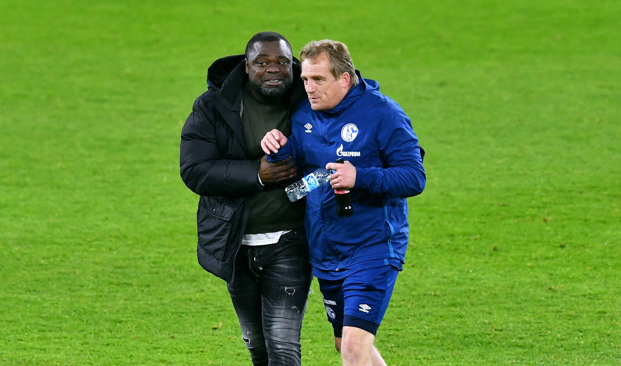 Asamoah und Büskens laufen Arm in Arm über das Feld.