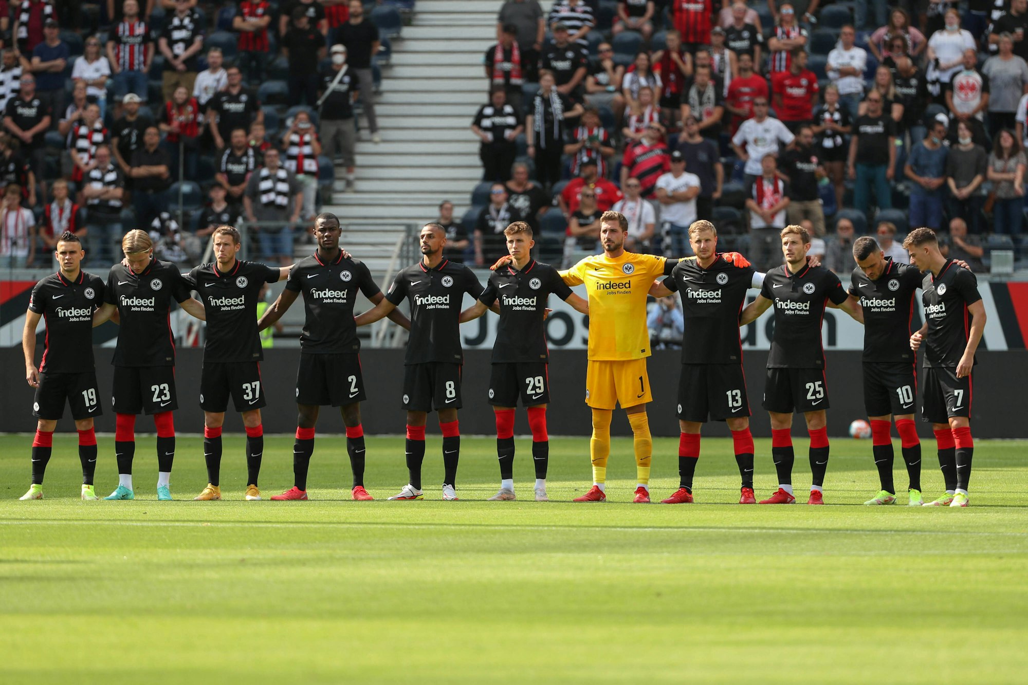 Die Startelf von Frankfurt steht Arm in Arm im Stadion der Eintracht.