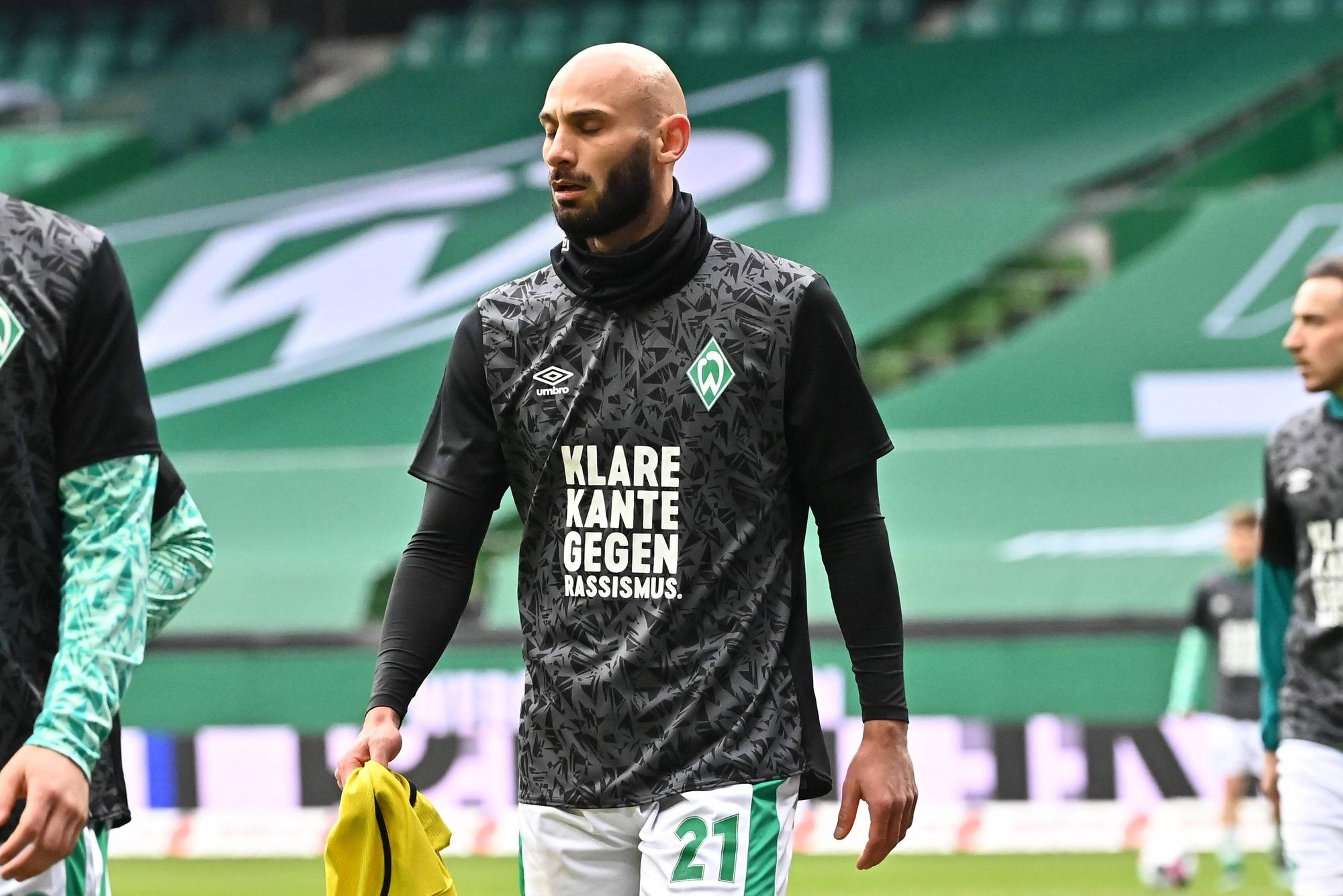 Ömer Toprak hat die Augen geschlossen und trägt ein dunkles Shirt mit der Aufschrift: „Klare Kante gegen Rassismus.“
