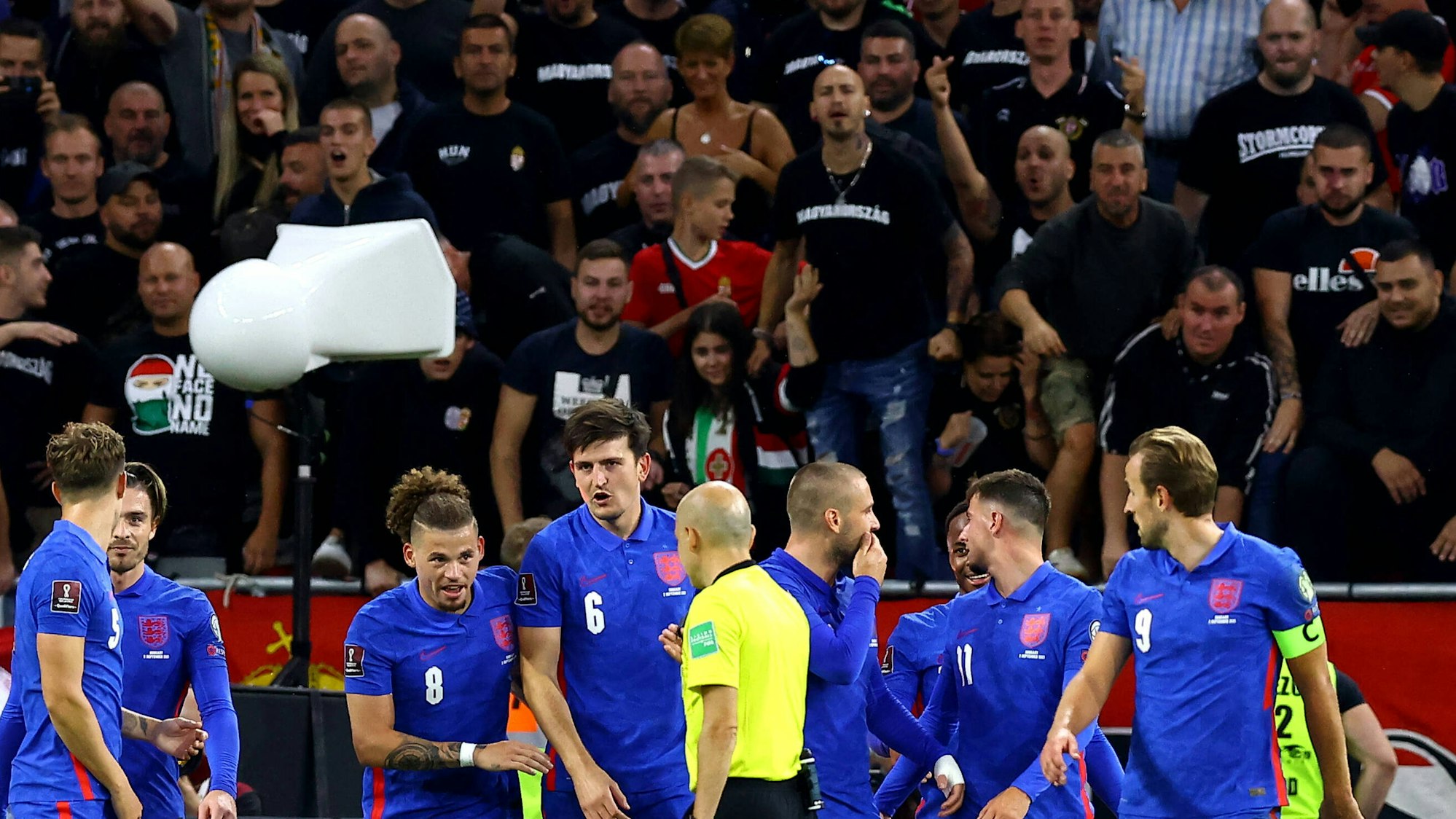 Englische Spieler stehen vor ungarischem Publikum, das sie beschimpft.
