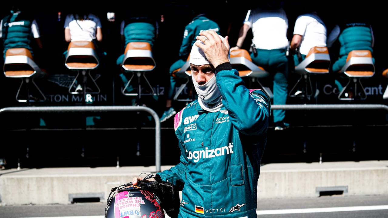 Sebastian Vettel mit Helm in der Hand und Gesichtsmaske auf dem Kopf fasst sich an den Kopf.