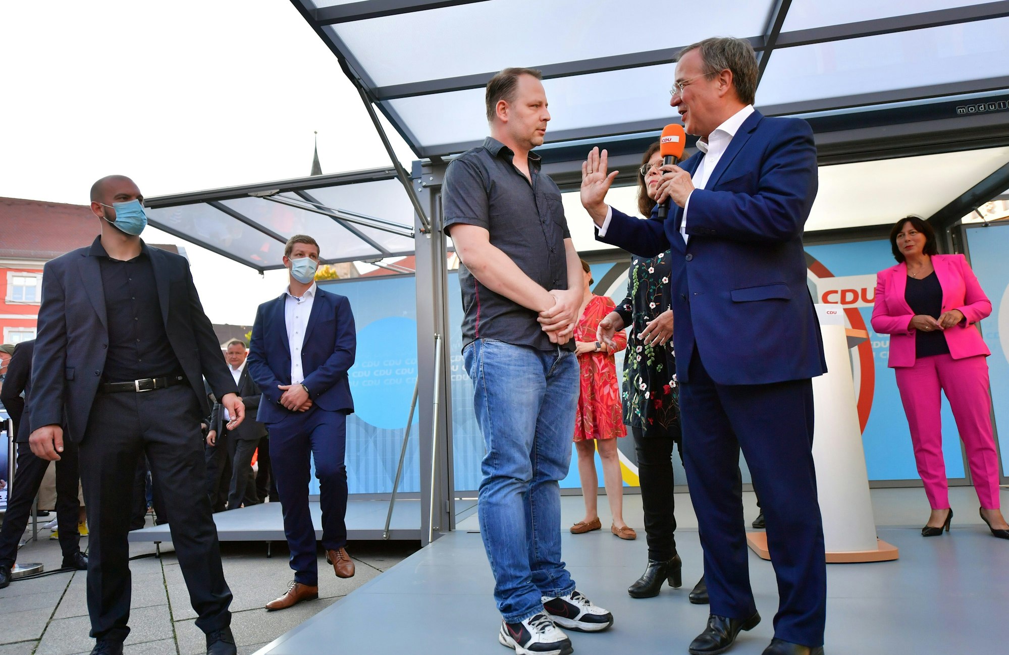 Armin Laschet, CDU-Kanzlerkandidat, spricht während einer Wahlkampfveranstaltung der CDU Thüringen mit einem Mann, der auf das Podium gekommen ist.