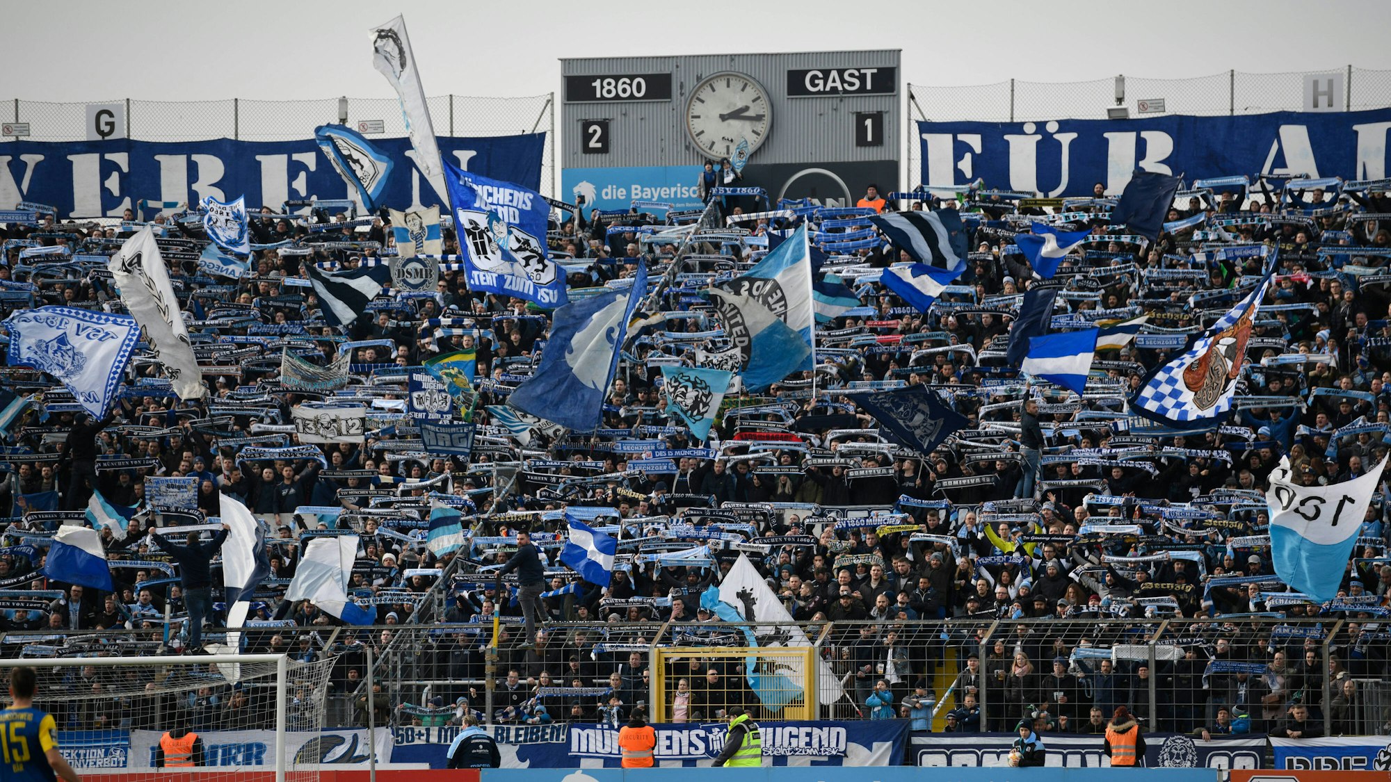 Die Fans des TSV 1860 München schwenken blaue Fahnen und zeigen ihre Schals beim Heimspiel im Grünwalder Stadion.