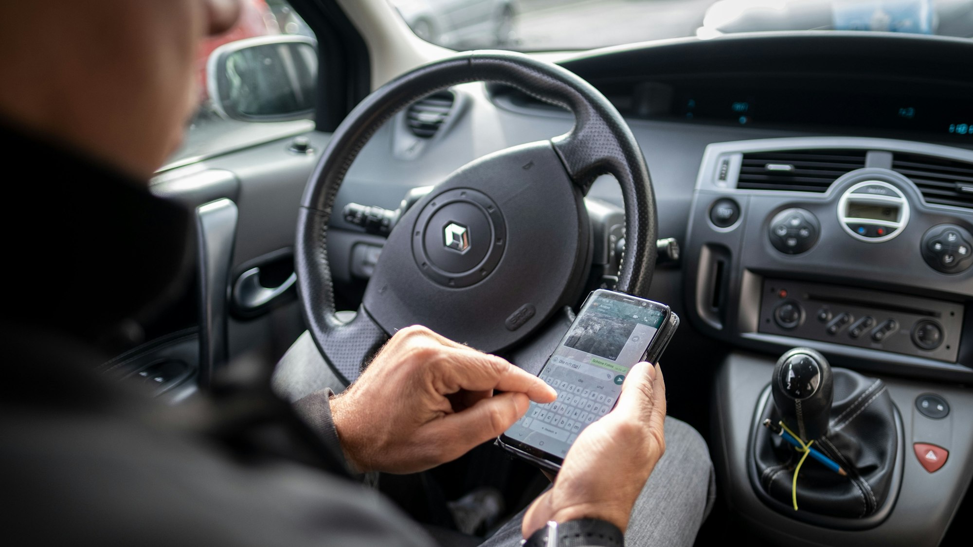 Völlig verfahren hat sich ein 92-jähriger Senior – eigentlich wollte er zur Einschulung seiner Enkelin. Er landete in Rostock und fuhr 550 Kilometer in die falsche Richtung. Unser Symbolbild zeigt einen Mann im Auto, der auf einem Smartphone eine Nachricht schreibt.