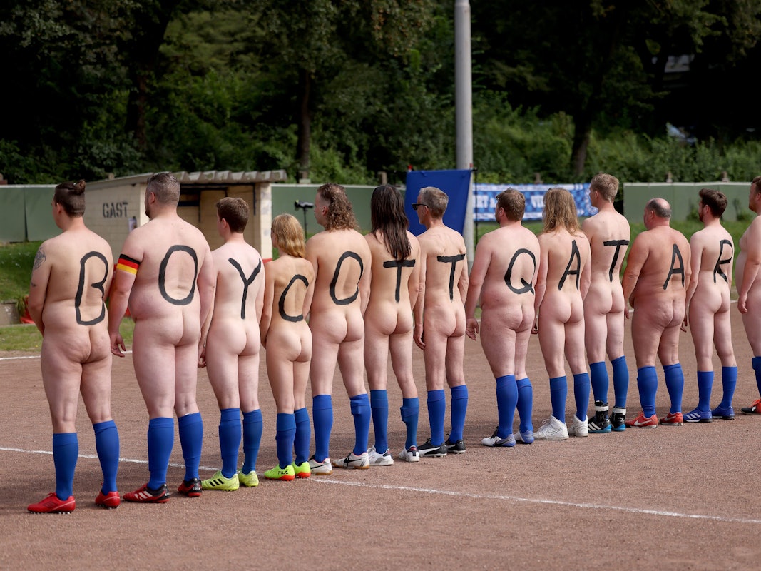 14 nackte Spielerinnen und Spieler drehen ihre Rücken zur Kamera. Sie tragen jeweils einen Buchstaben bzw. eine Ziffer auf dem Rücken. Zu lesen ist: Boycott Qatar 22.