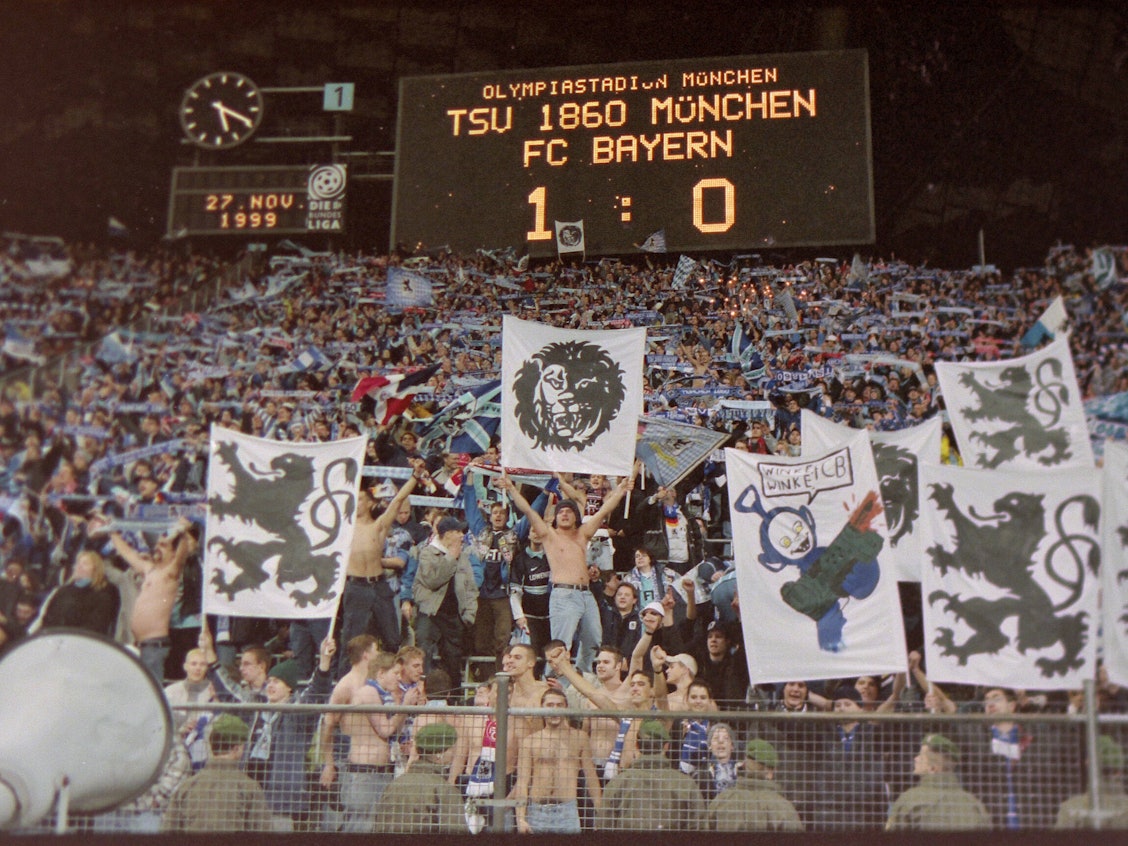 Auf der Anzeigetafel steht, dass 1860 mit 1:0 gegen Bayern gewonnen hat. Darunter freuen sich die Fans der Löwen.