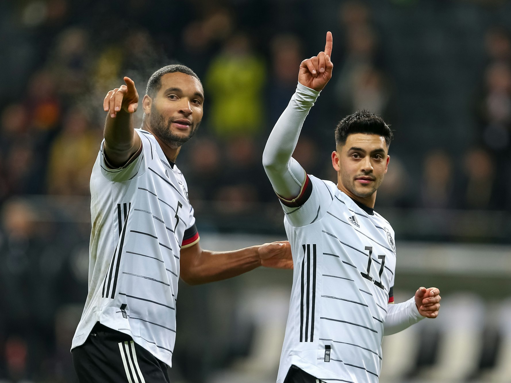 Nadiem Amiri und Jonathan Tah heben ihre Zeigefinger.