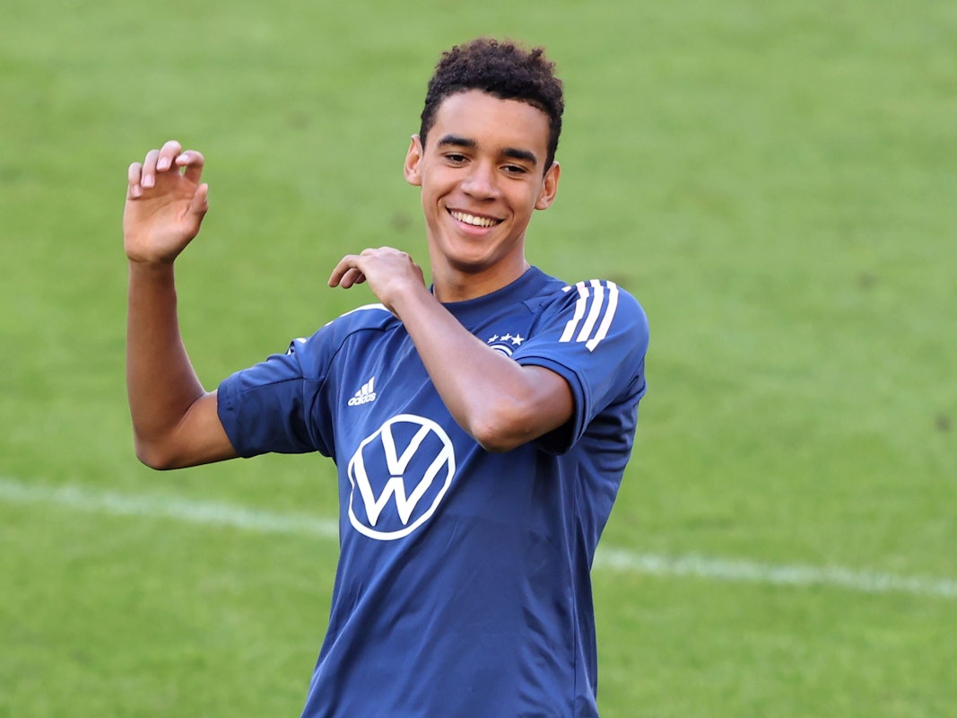 Jamal Musiala steht lachend auf dem Platz