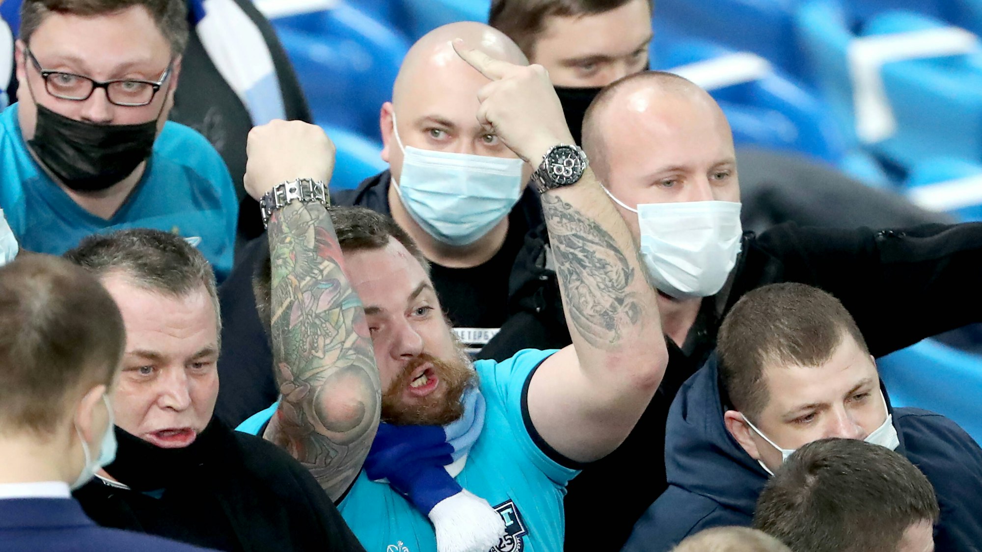 Mehrere Zenit-Fans stehen nebeneinander, einer von ihnen ballt die eine Faust und zeigt mit der anderen den Mittelfinger.