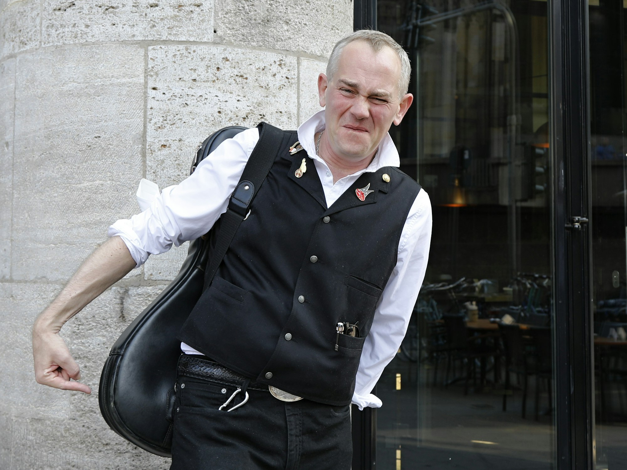 JP Weber verzieht das Gesicht und zeigt mit seinem Finger auf seinen Allerwertesten.