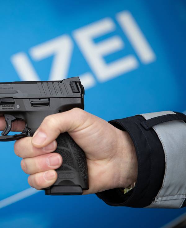 Ein Polizist hält eine Dienstwaffe in der Hand.