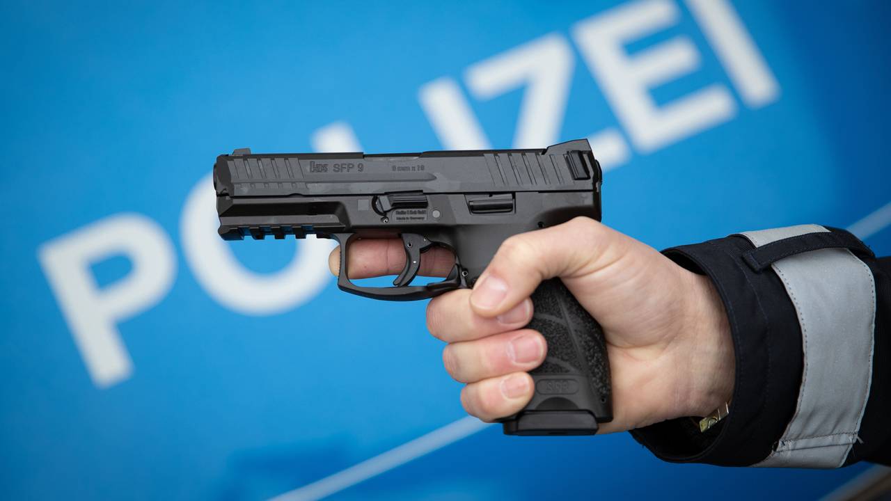 Ein Polizist hält eine Dienstwaffe in der Hand.