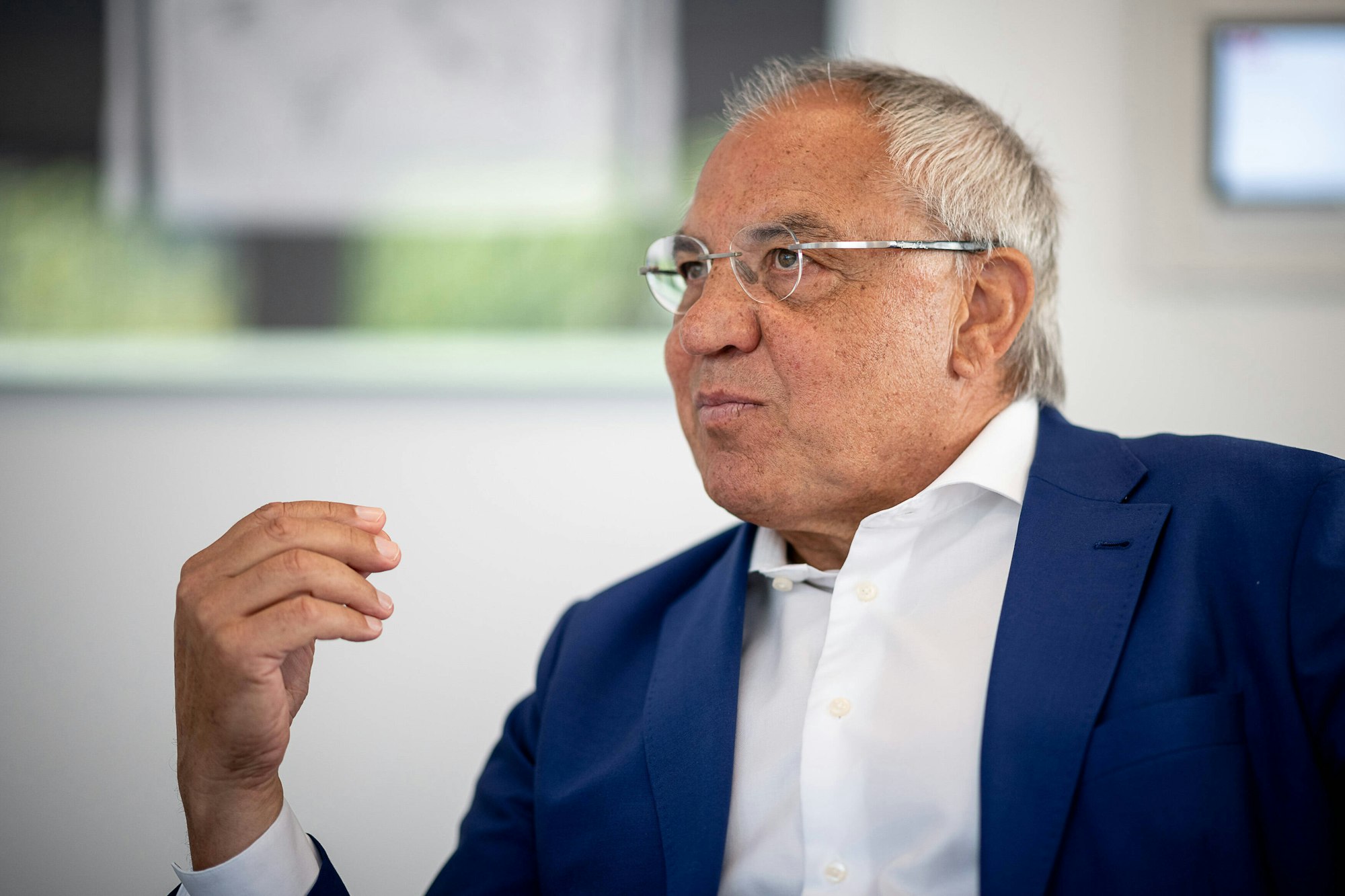 Felix Magath sitzt und gestikuliert mit der rechten Hand.