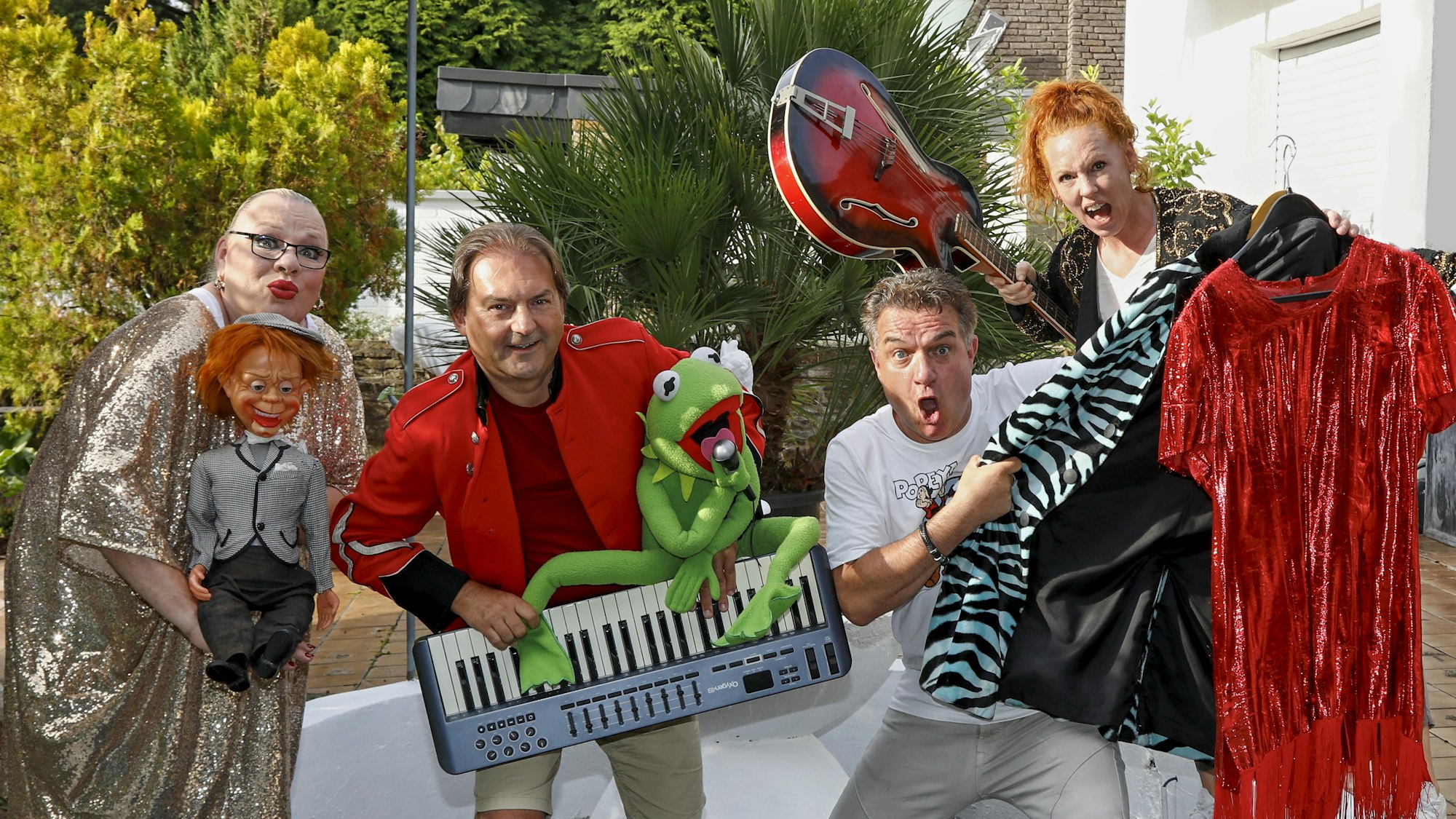 Sophie Russel, Peter Paschek, Linus und Katja Baum schneiden Grimassen und präsentieren im Garten Keyboard, Gitarre und Requisiten.