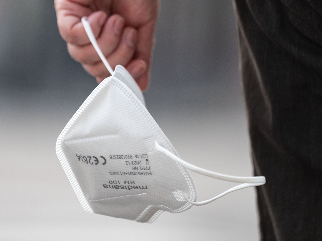Eine Passantin trägt eine FFP2-Maske in der Hand.