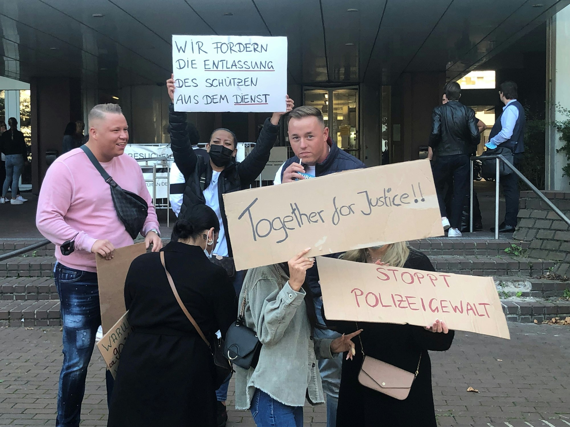 Demonstranten halten Schilder mit Aufschriften vor dem Kölner Landgericht.