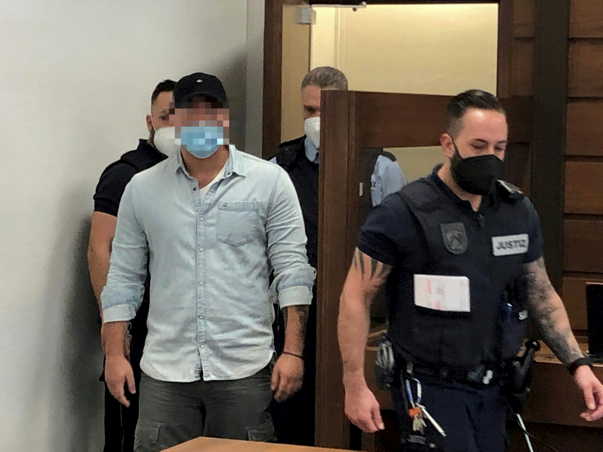 Der Nebenkläger wird von Justizbeschäftigten in den Gerichtssaal begleitet.