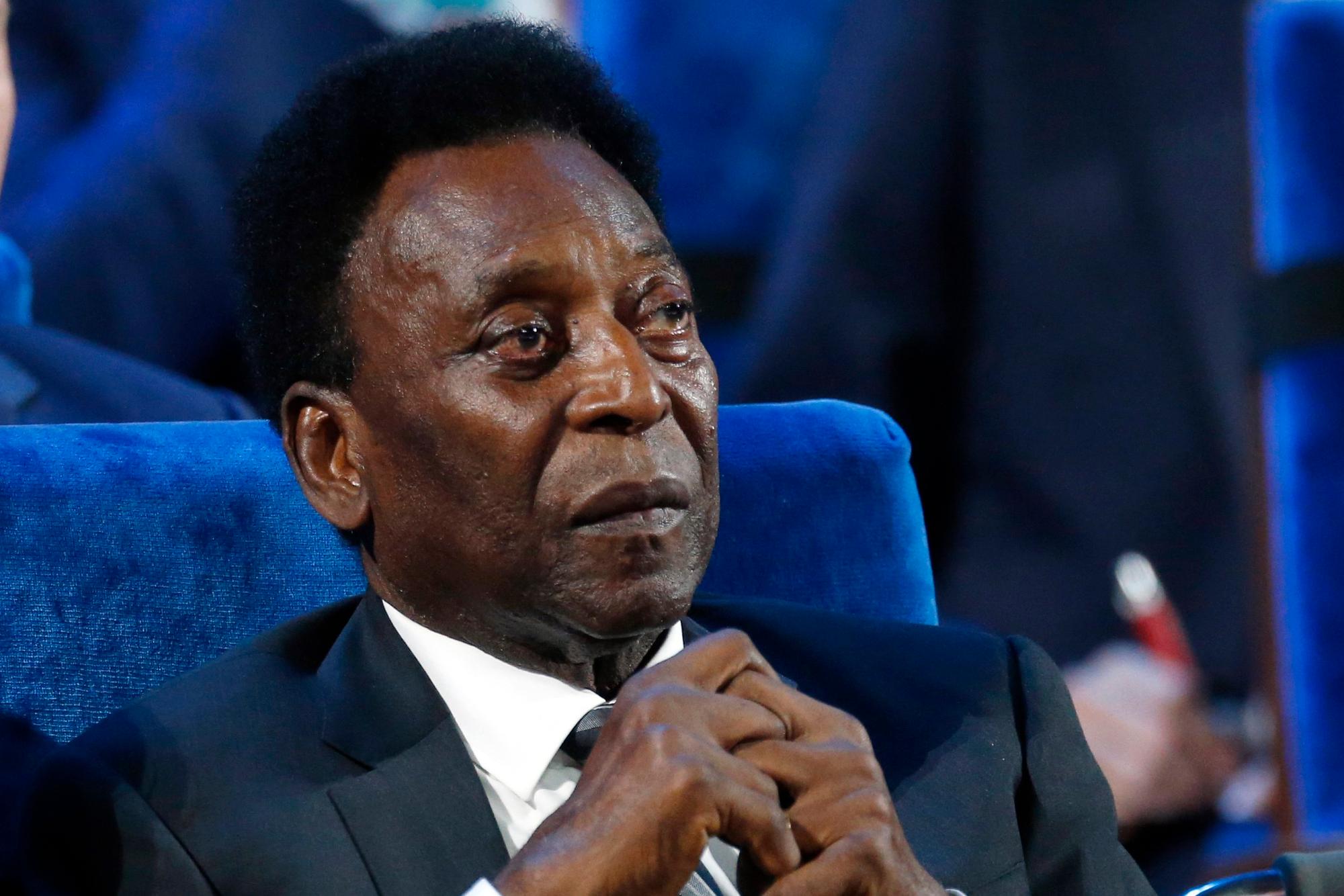 Pele sitzt mit verschränkten Fingern in einem blauen Sessel