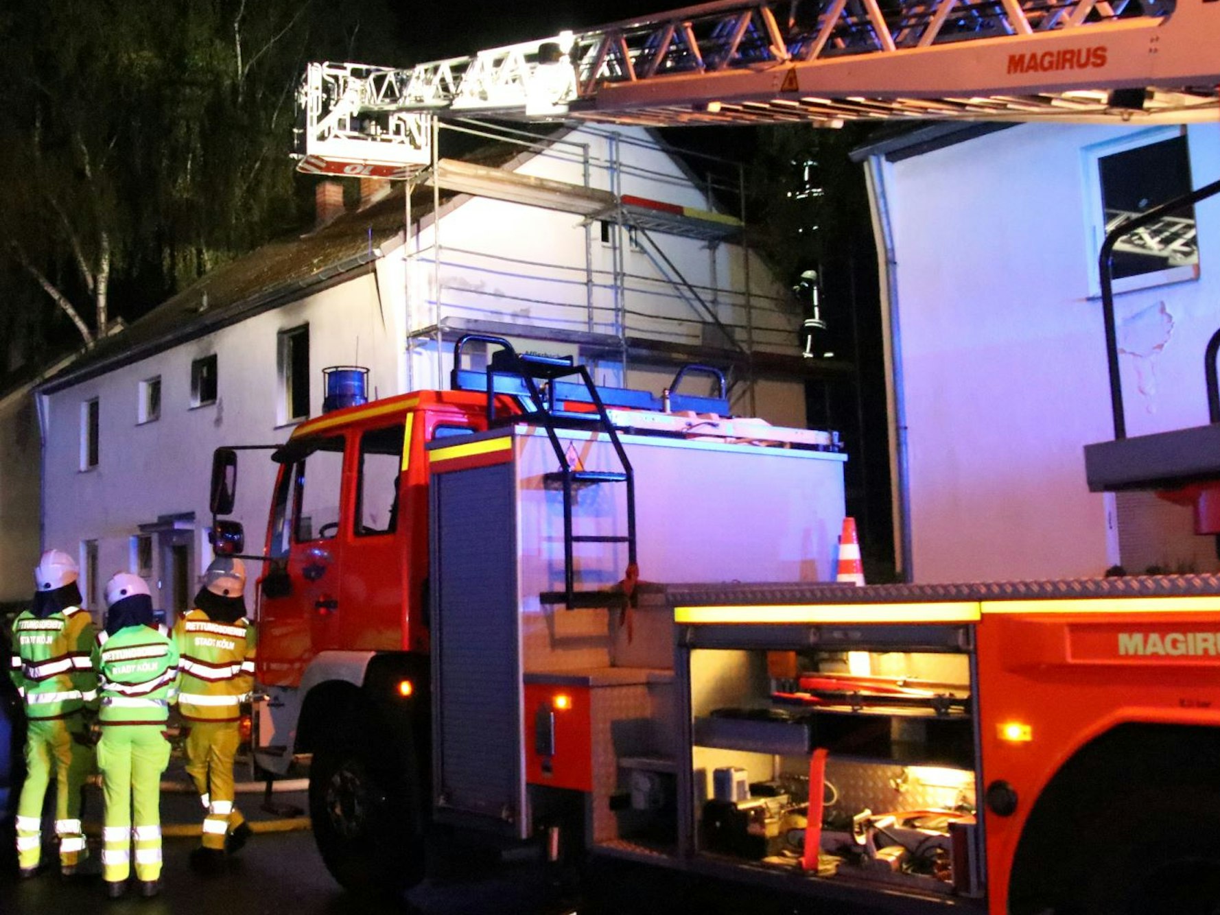 Einsatzkräfte der Feuerwehr sind mit einem Drehleiter-Wagen vor dem Brandhaus.