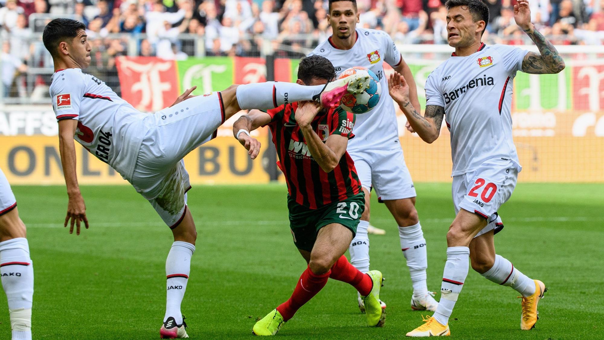 Dreikampf in Augsburg: Exequiel Palacios und Charles Aranguiz stoppen Daniel Caligiuri.