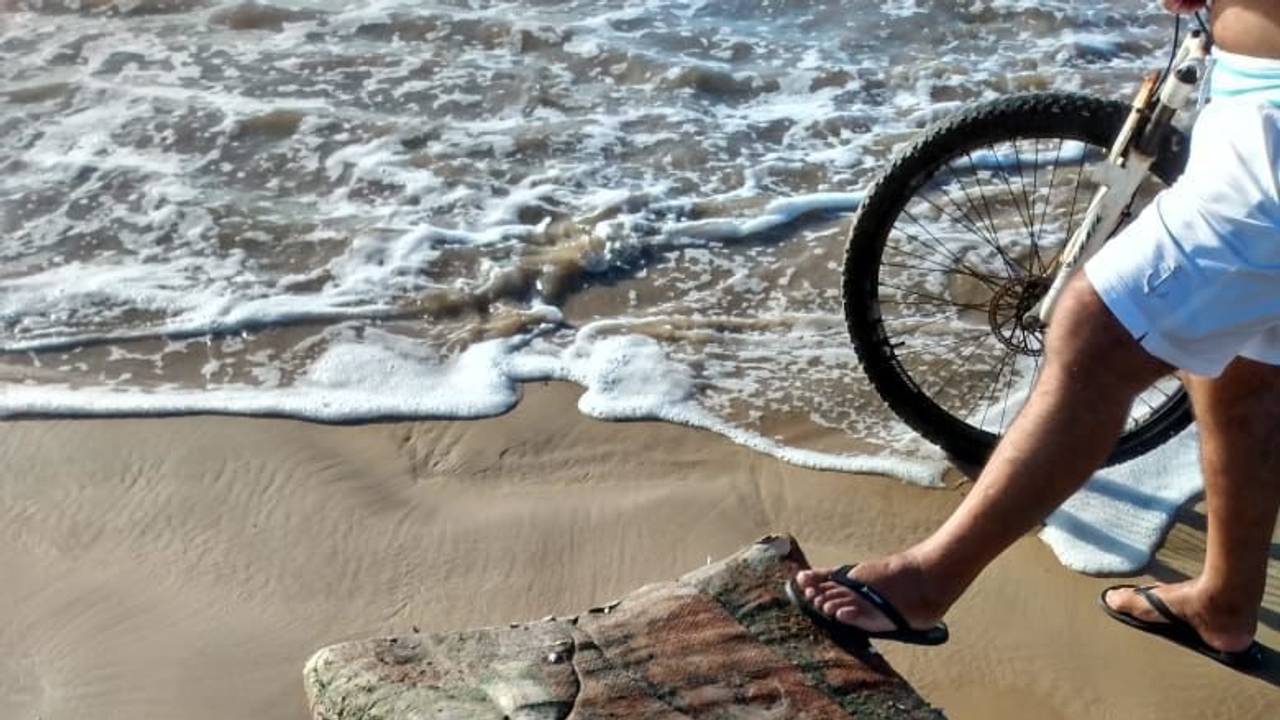 Ein Passant stellt seinen Fuß am Strand von Brasilien auf eine mysteriöse Kiste