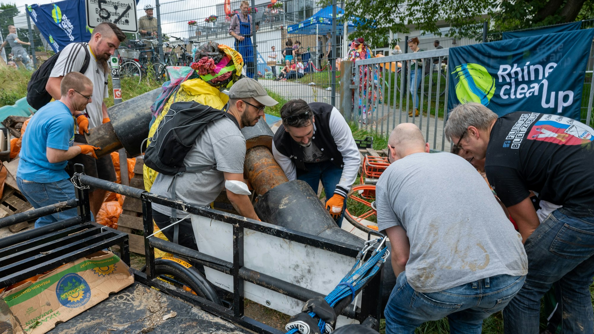 Freiwillige sammeln Müll am Rheinufer.