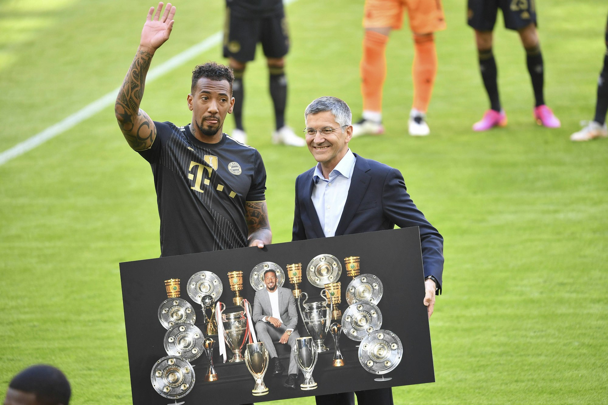 Bayerns Jerome Boateng winkt zum Abschied den Fans. An seiner Seite steht Herbert Hainer, sie halten ein Bild, das Boateng und die von ihm gewonnen Pokale und Titel abbildet.