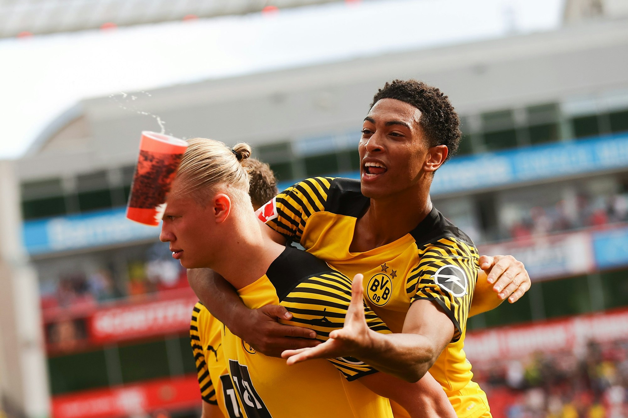 Jude Bellingham von Borussia Dortmund fängt beim Torjubel einen Bierbecher